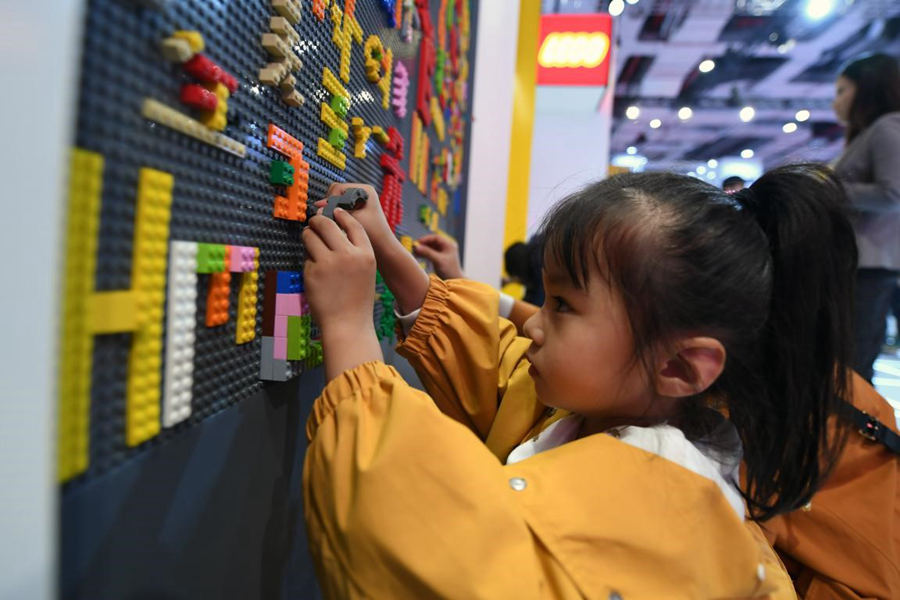 A girl plays with Lego blocks at the quality life section of the second CIIE. (Photo by Weng Qiyu from People’s Daily)