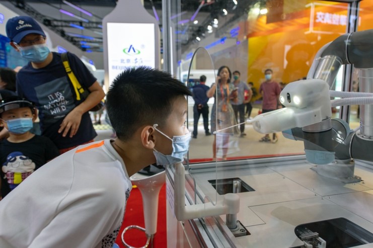 Photo taken on September 6 shows a boy watches a throat swab sample collecting robot at the thematic exhibition zone for public health and epidemic prevention of the China International Fair for Trade in Services (CIFTIS). (Photo by Weng Qiyu/People’s Daily Online)