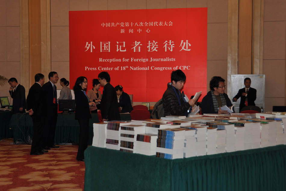 Journalists pick up free books provided by the Press Center of the 18th National Congress of the CPC. (People’s Daily Online/Yan Meng)