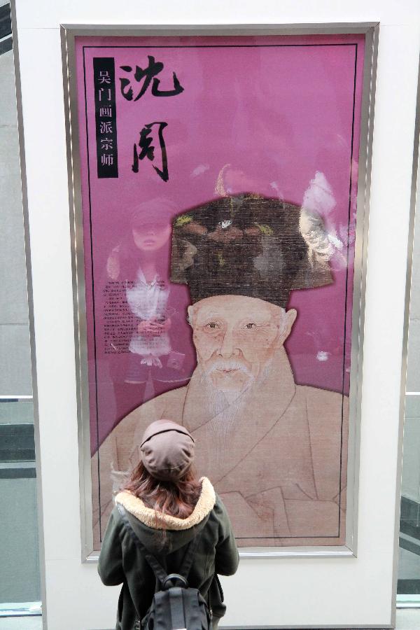 A visitor watches a poster of an exhibition of ancient Chinese calligraphy and painting works at Suzhou Museum in Suzhou of east China's Jiangsu Province, Nov. 6, 2012. (Xinhua/Chen Yu) 