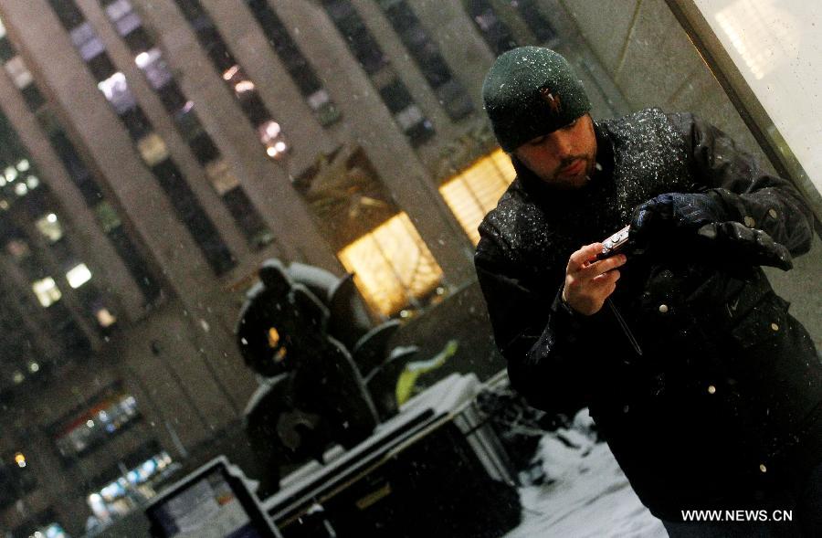 A man check photos on a camera by on the 5th Avenue in New York, the United States, Nov. 7, 2012. As New Jersey and New York are still trying to recover from the damage created by Hurricane Sandy, a Nor'easter named Winter Storm Athena dropped snow and rain on the Northeast on Wednesday, also bringing dangerous winds and knocking out power. (Xinhua/Wu Jingdan)