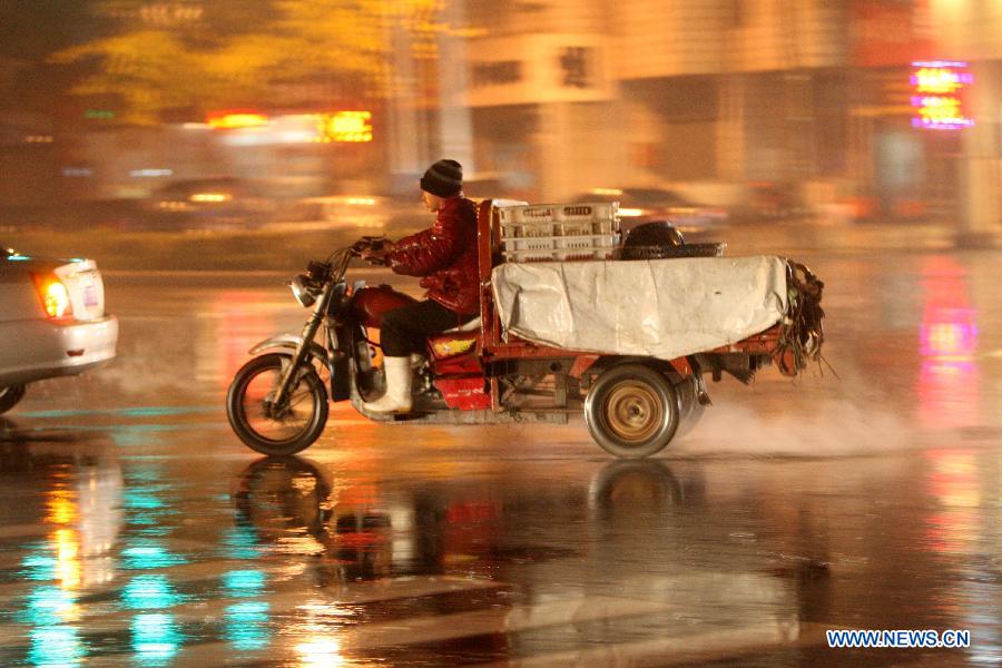 A man rides a motor tricycle in the rain on Shengli Road of Yantai City, east China's Shandong Province, Nov. 10, 2012. A strong cold snap brought rainfall and wind to the coastal city, causing a fall in temperature. (Xinhua/Shen Jizhong)