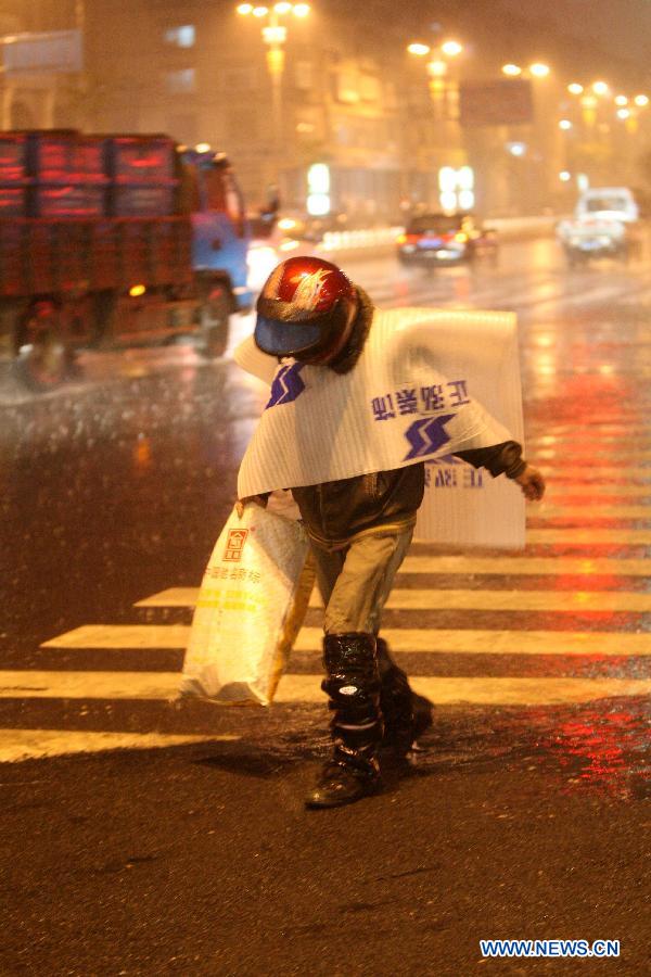 A citizen walks against the rain on Beima Road of Yantai City, east China's Shandong Province, Nov. 10, 2012. A strong cold snap brought rainfall and wind to the coastal city, causing a fall in temperature. (Xinhua/Shen Jizhong)