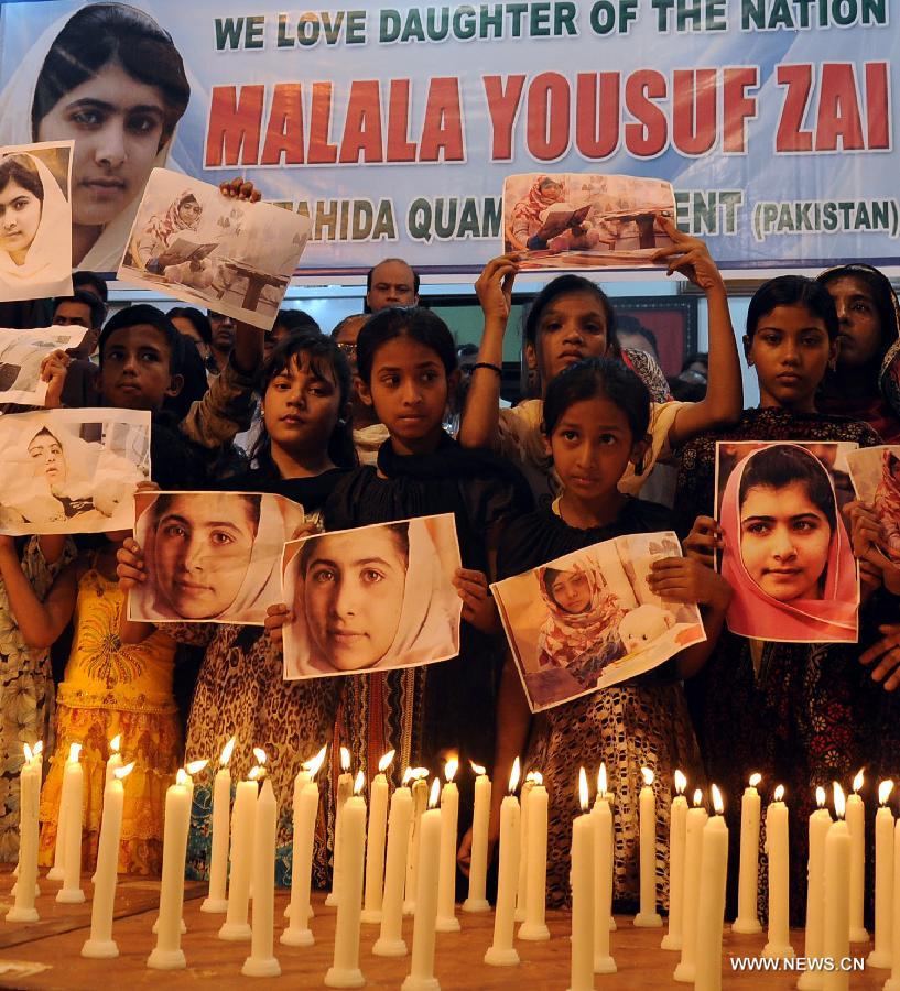 Children hold photos of Pakistan's child activist Malala Yousafzai as they stand alongside burning candles during a ceremony to mark "Malala Day" in Karachi, Pakistan, Nov. 10, 2012. (Xinhua/Masroor)