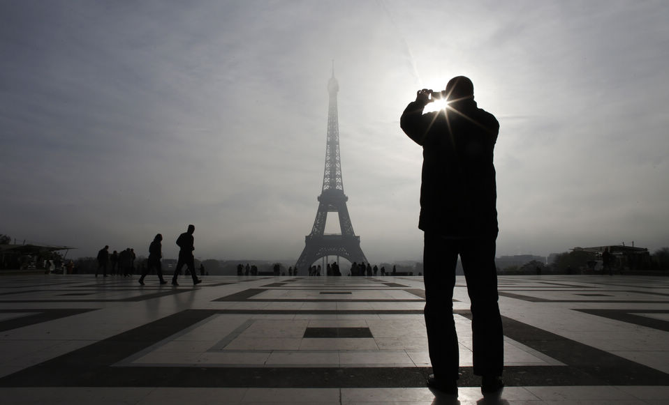A tourist takes photos in front of the Eiffel Tower in Pairs, France on November 9, 2012. (Xinhua/Reuter)
