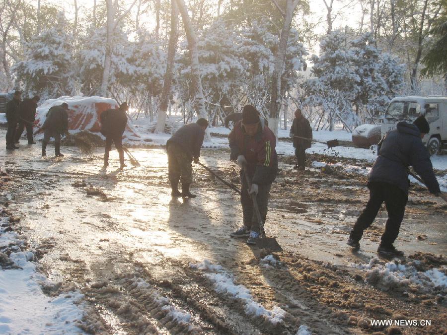 People clean snow on a road in Shenyang, capital of northeast China's Liaoning Province, Nov. 12, 2012. A cold front is sweeping across the country's northern areas, bringing heavy snow and blizzards. (Xinhua/Cao Yang)  