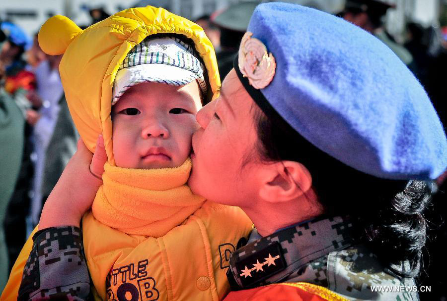 A member of the medical team of the 14th batch of Chinese peacekeeping force for Liberia kisses her child during a departure ceremony in Tianjin, north China, Nov. 13, 2012. The first batch of a 43-member Chinese medical personnel group left for Liberia on a eight-month UN peacekeeping mission here on Tuesday. (Xinhua/Zhang Chaoqun)