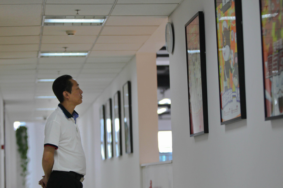 Wang Jin looks at an animation poster in the Program Production Center of China ACG Group Co., Ltd in Beijing, capital of China, April 19, 2012. (Xinhua/Meng Chenguang)