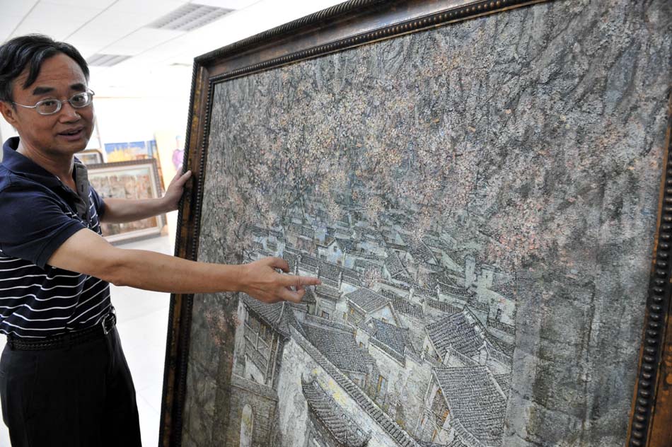 Yu Chunming introduces his painting in Nanchang, capital of east China's Jiangxi Province, Sept. 2, 2012. (Xinhua/Song Zhenping)