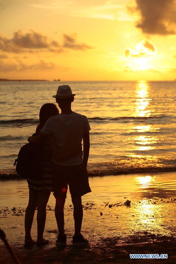 A pair of lovers enjoy the sunset on a beach in Sanya, south China's island of Hainan Province, Nov. 20, 2012. Though the winter draws near, the tropic seaside city of Sanya remains warm and attracts many tourists. (Xinhua/Chen Wenwu)