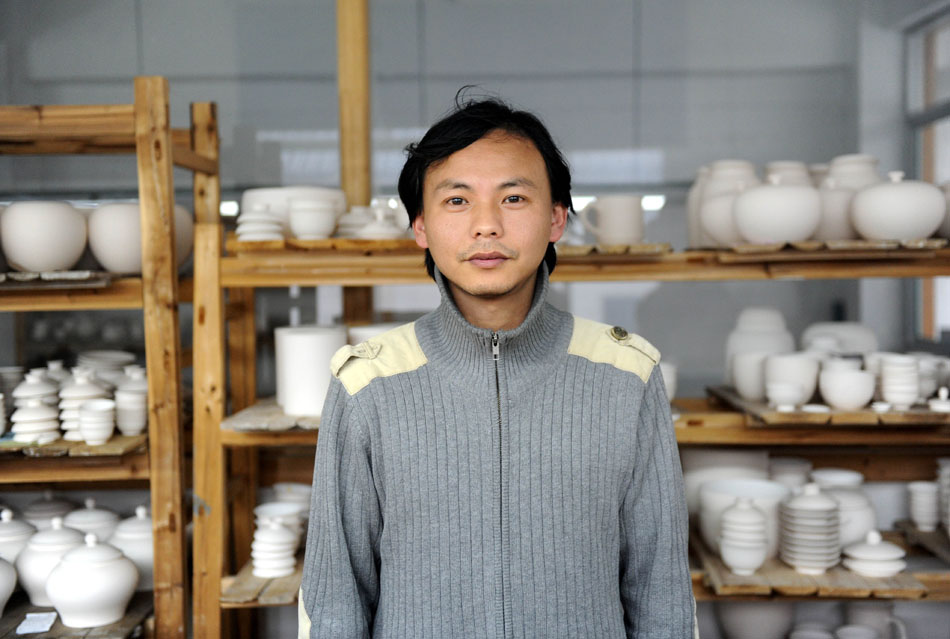 Liu Zhen poses with the porcelain adobes in his studio at the Chengdexuan Porcelain Co.,Ltd, in Jingdezhen of east China's Jiangxi Province, March 8, 2012. (Xinhua/Zhou Ke)