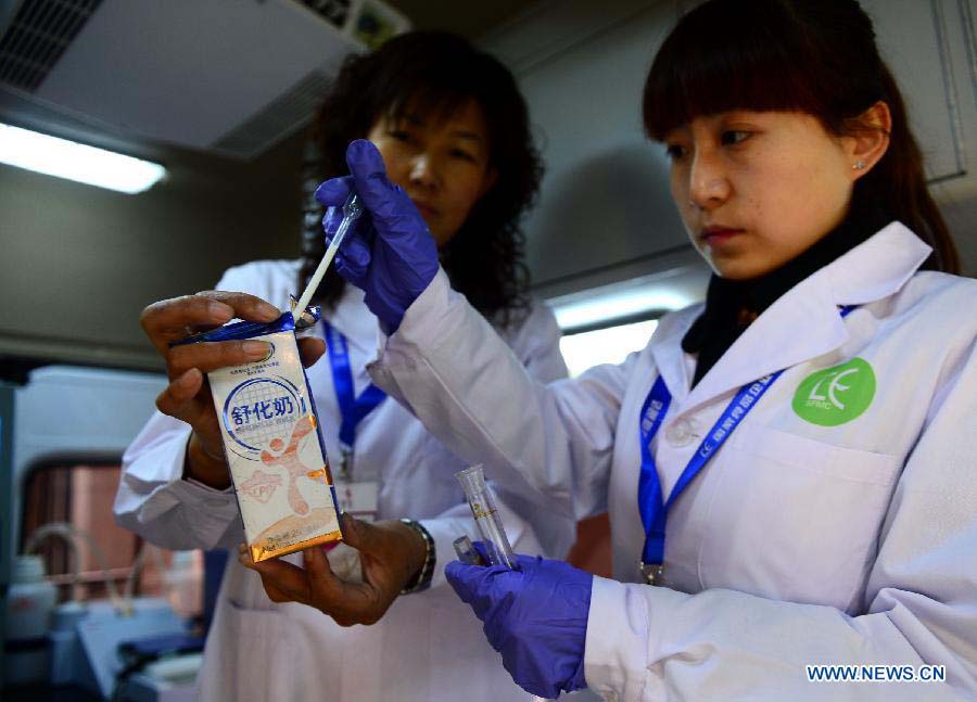 Two researchers test the ingredients of dairy products in the newly-developed intelligent vehicle for food detection in Lanzhou, capital of northwest China's Gansu Province, Nov. 21, 2012. The intelligent vehicle can conduct various kinds of food tests on site. (Xinhua/Zhang Meng)