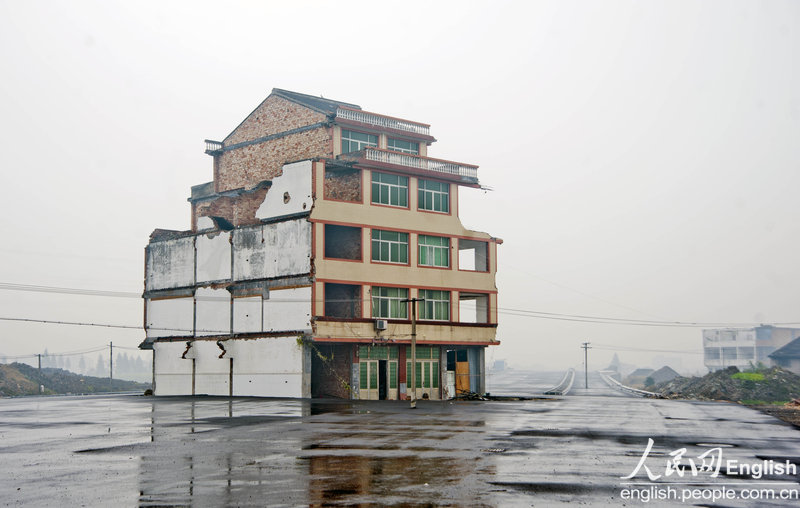 A five-story house stands in the middle of the road to the Railway Station of Wenling．People who are dissatisfied with the relocation compensation still live inside. Vehicles have to bypass the house to get through although the road has not been put into use. (CFP)