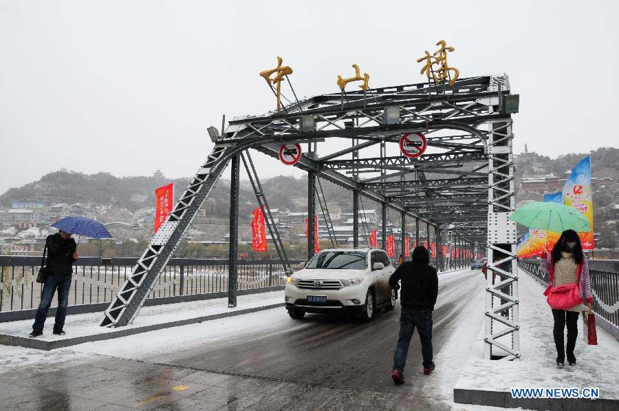 Cars and pedestrians pass through a bridge in snow in Lanzhou, capital of northwest China's Gansu Province, Nov. 22, 2012. The province was hit by snow and temperature decrease on Thursday.(Xinhua/Fan Peishen) 