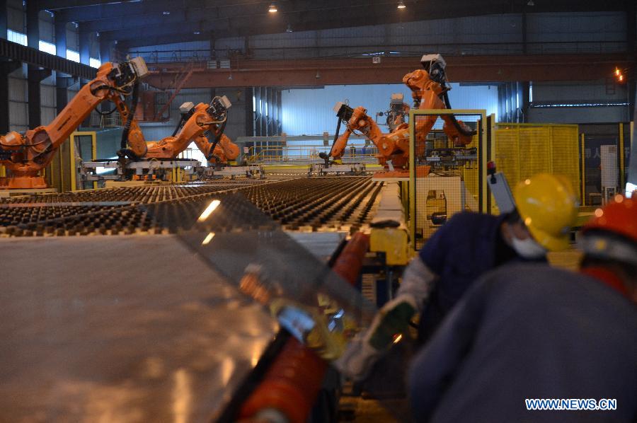 Workers and robots work on the production line in Hongyu energy company in Zhangshu, east China's Jiangxi Province, Nov. 22, 2012. The company has invested 350 million yuan (56.1 million dollars) and built the largest energy efficiency glass production line in China. (Xinhua/Zhou Mi) 