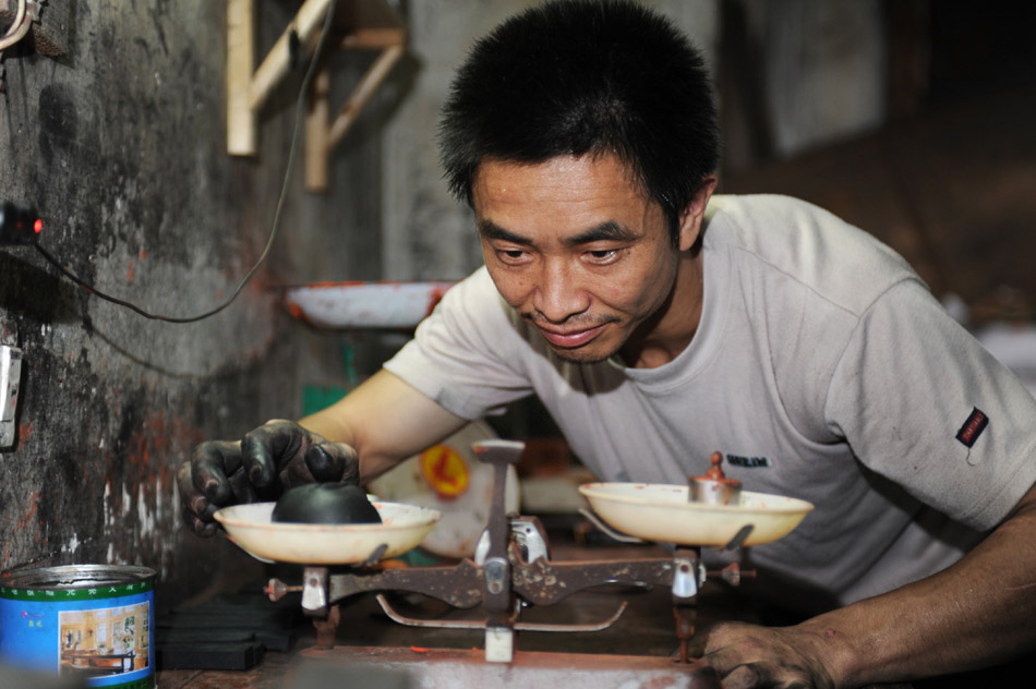 Huang Jun, a skilled worker in Xiang Shengli's inksticks factory, weighs the inksticks mud in Shexian County of east China's Anhui Province, Aug. 11, 2012. (Xinhua/Du Yu)