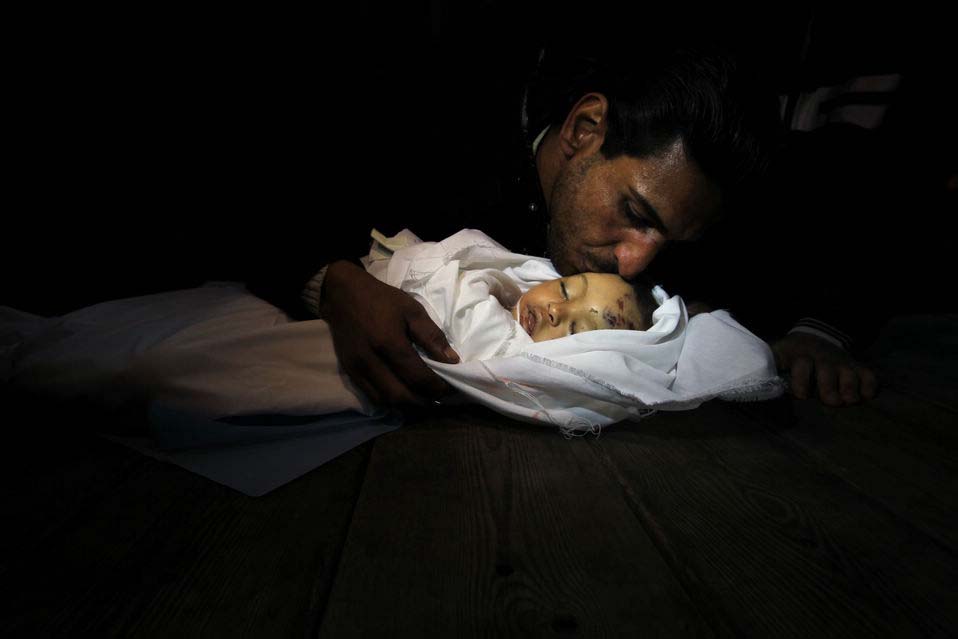 A sad man kisses the baby girl in mortuary of a hospital in Gaza City, on Nov. 15, 2012. (Xinhua/AFP)