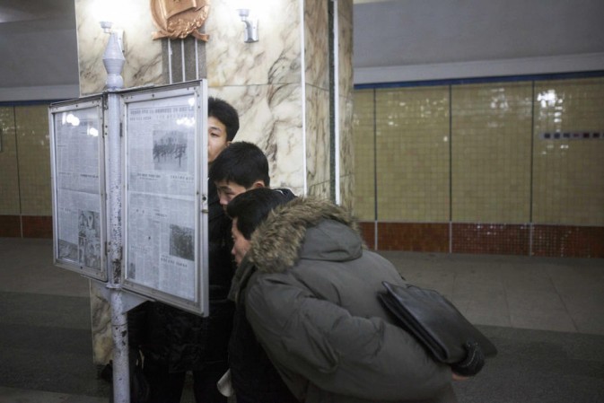 A public display of newspaper in the station. People bent over to read the newspaper.(Photo/Xinhua)