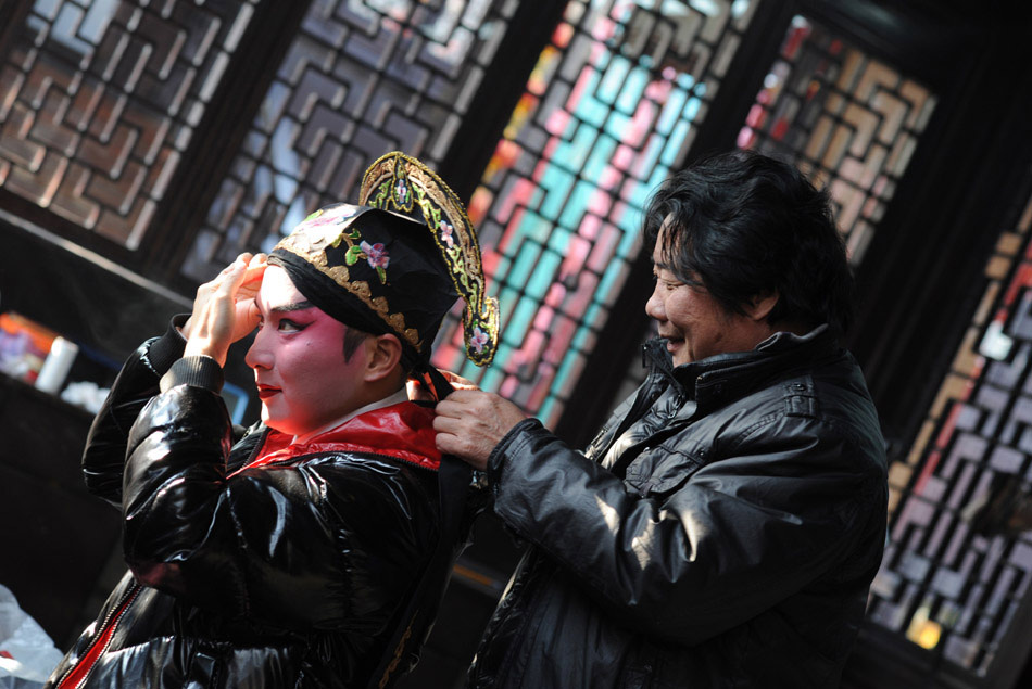Zeng Jie (L) gets his makeup on before a show in Zhouzhuang, east China's Zhejiang Province, Dec. 10, 2011. (Xinhua)