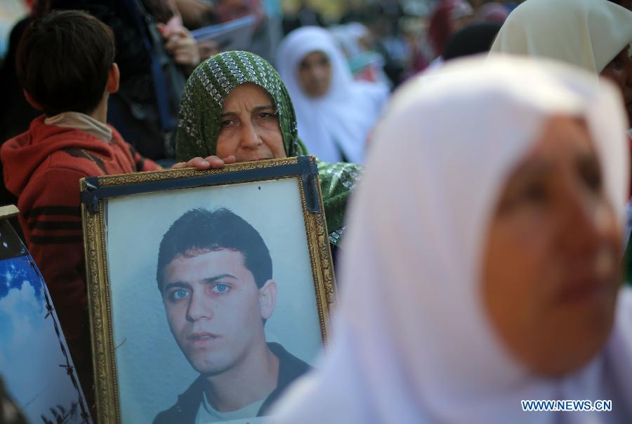 A Palestinian woman holds a poster of Palestinian prisoner during a protest calling for the release of them from Israeli jails and in support of prisoners on hunger strike in front of Red Cross, in Gaza city, on Nov. 26, 2012. Some 4,600 Palestinians prisoners are still in the Israeli prisons. (Xinhua/Wissam Nassar)