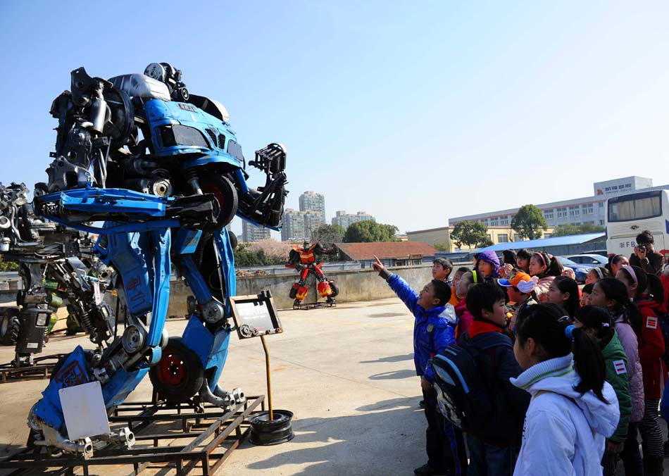 Pupils are attracted by a steel artwork at the Mr. Iron Robot Theme Park in Jiaxing, east China's Zhejiang Province, March 24, 2012. 