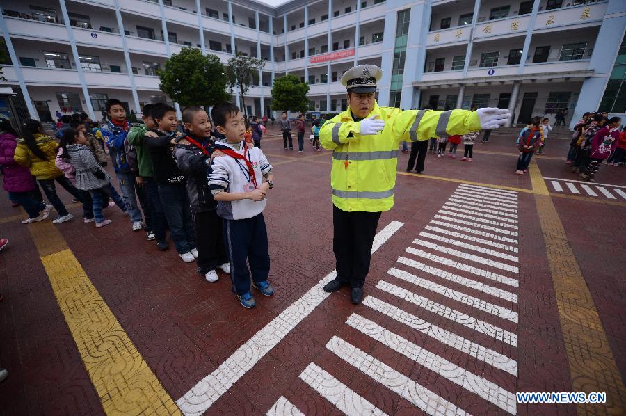 A traffic policeman shows the pupils how to direct the traffic at the Wan'an Experimental Primary School in Wan'an County, east China's Jiangxi Province, Nov. 28, 2012. 