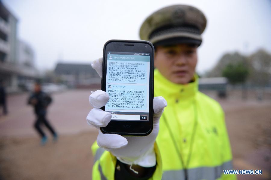 A police officer shows the messages sent to schools about road traffic information in Wan'an County, east China's Jiangxi Province, Nov. 28, 2012.
