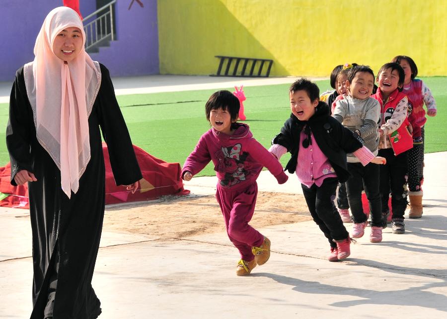 A teacher and children play games at a kindergarten in Dahejia Township of Linxia Hui Autonomous Prefecture, northwest China's Gansu Province, Nov. 29, 2012. A total of 253 children from various ethnic groups study and live at the kindergarten. (Xinhua/Huang Wenxin) 