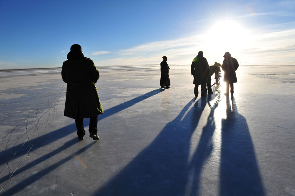 Tourists stand on thick ice layer formed over China’s largest inland salt water lake Qinghai Lake on Nov. 27, 2012. (Xinhua/Zhang Jiansong)