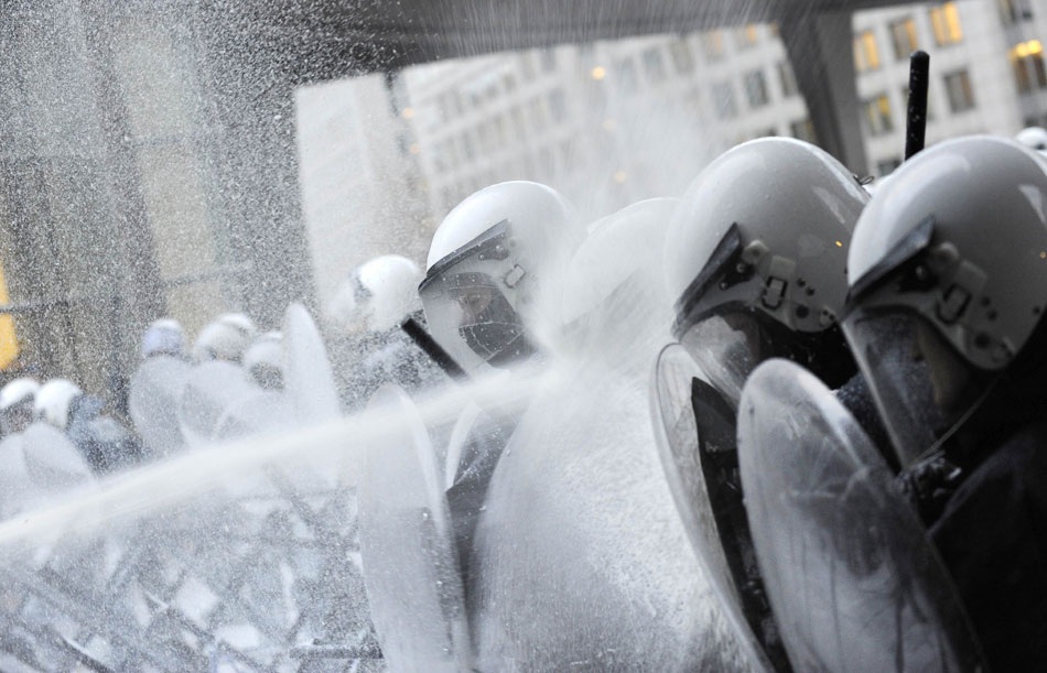 Policemen with helmets and shields confront protesting dairy farmers and their powerful milk “cannon” outside the building of European Parliament in Brussels, Nov. 26, 2012. Approximately 2,000 European dairy farmers joined the protest to express their dissatisfaction to the underpriced milk price (Xinhua/AFP)