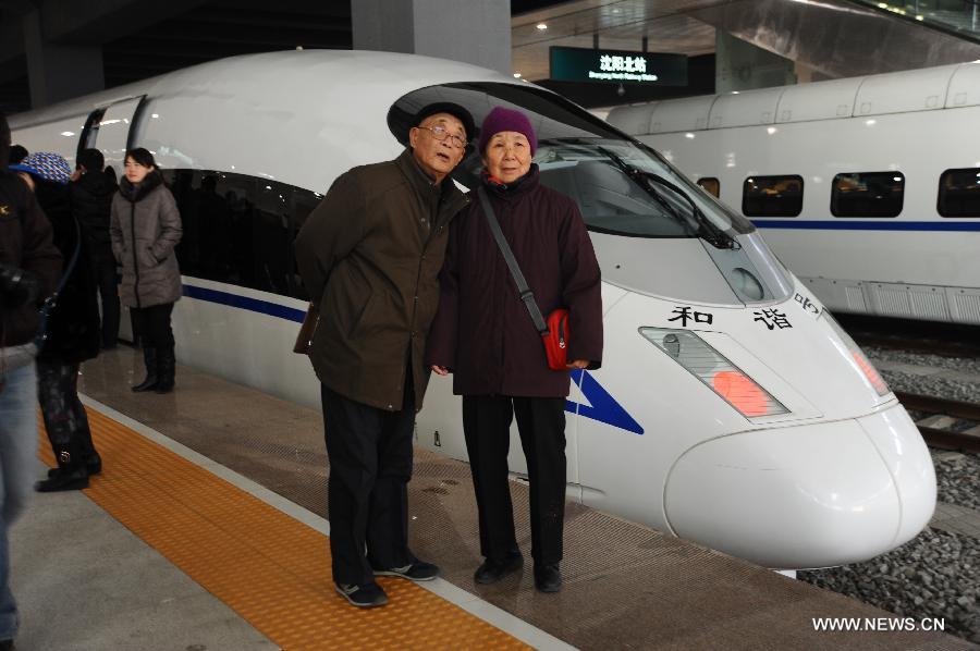 A couple pose for pictures in front of a D5008 high-speed train at the Shenyang North Railway Station in Shenyang, capital of northeast China's Liaoning Province, Dec. 1, 2012. The world's first high-speed railway in areas with extremely low temperature, which runs through Liaoning, Jilin and Heilongjiang provinces in northeastern China, started operation on Saturday. The railway links Harbin, capital of Heilongjiang , and Dalian, a port city in Liaoning. (Xinhua/Li Chengzhi)