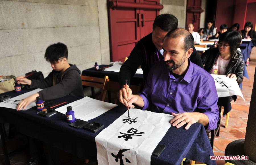 An Italian tourist (front) experiences writing Chinese calligraphy during an activity at Taipei Confucius Temple in Taipei, southeast China's Taiwan Province, Dec. 2,2012. (Xinhua/Wu Ching-teng) 