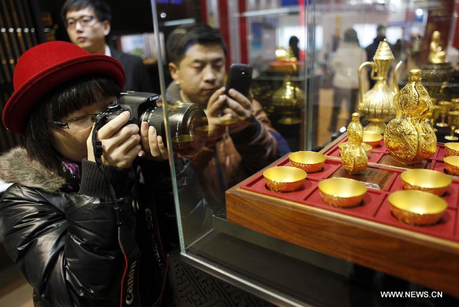 Visitors take photos of a work of art which is made of gold at the 8th Beijing International Finance Conference in Beijing, capital of China, Dec. 3, 2012. The four-day conference was closed on Monday. (Xinhua/Wang Shen)