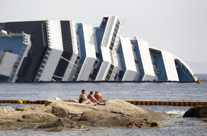 Vacationers bask in the sun beside the sinking Costa Concordia cruise on June 20, 2012. (Reuters/Max Rossi) 