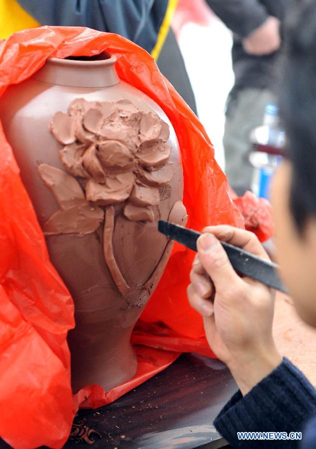 A contestant carves on a ceramic bottle during a contest for ceramics-making in Qinzhou City, south China's Guangxi Zhuang Autonomous Region, Dec. 6, 2012. Altogether 142 contestants took part in the event. (Xinhua/Chen Ruihua)