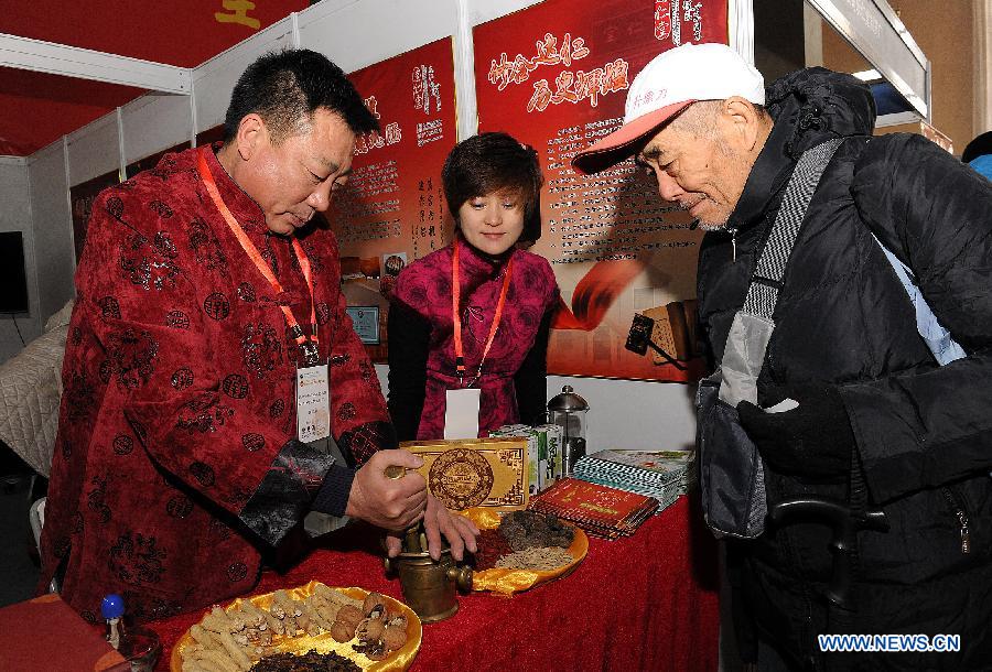 Exhibitors introduce the process of making Chinese medicine to a visitor during the China Traditional Chinese Medicine Culture and Industry Expo 2012 in Beijing, capital of China, Dec. 6, 2012. The three-day event kicked off at Beijing Exhibition Center on Thursday. (Xinhua/He Junchang)
