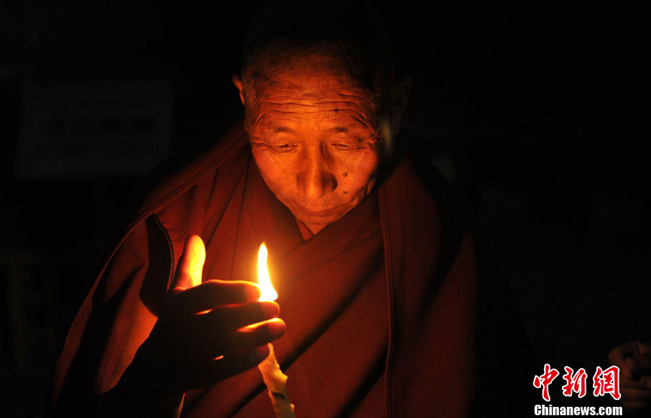 Photo shows an old devotee lighting a butter lamp. (Chinanews.com/ Li Lin)
