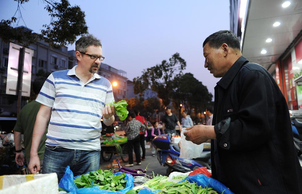 Anatoly Burov (L) buys vegetables near his residence in Shanghai, east China, May 6, 2012. (Xinhua/Lai Xinlin) 