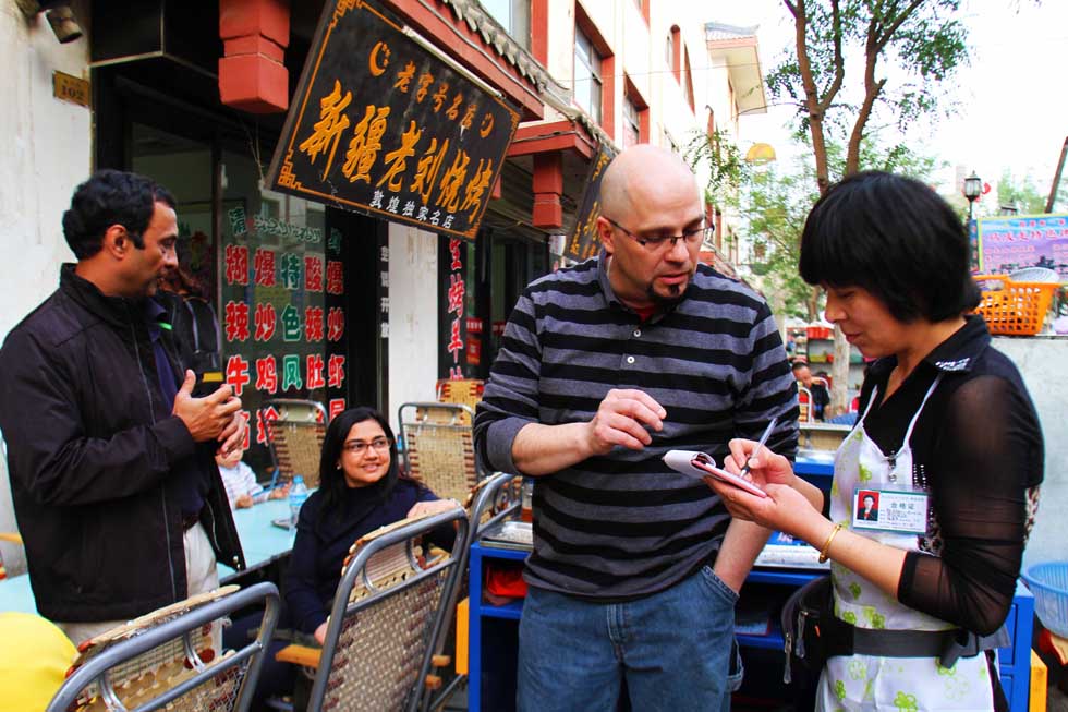 Kevin Gilley (C) helps two Indians who can't speak Chinese order dishes at a barbeque restaurant in Dunhuang, northwest China's Gansu Province, April 29, 2012. 