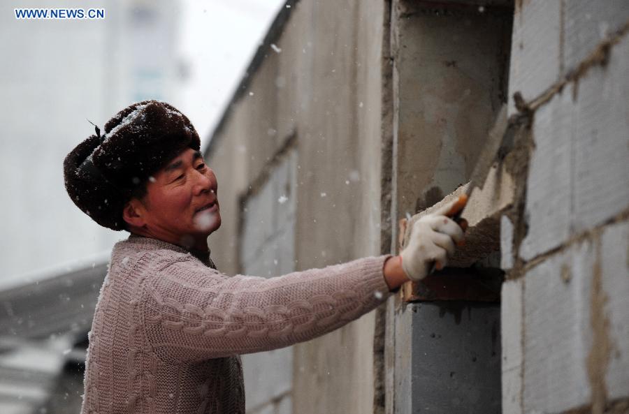 A worker does his job in snow in Tiantongyuan, Beijing, capital of China, Dec. 12, 2012. A snow hit China's capital city on Wednesday. (Xinhua/Yin Bogu)