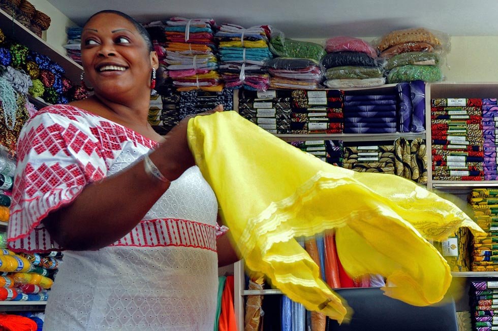 Senegalese merchant Mamadou Sall's wife Fatima presents cloth for sale in Sall-Industrial Co., Ltd. in Yiwu, east China's Zhejiang Province, July 15, 2012.(Xinhua/Tan Jin) 