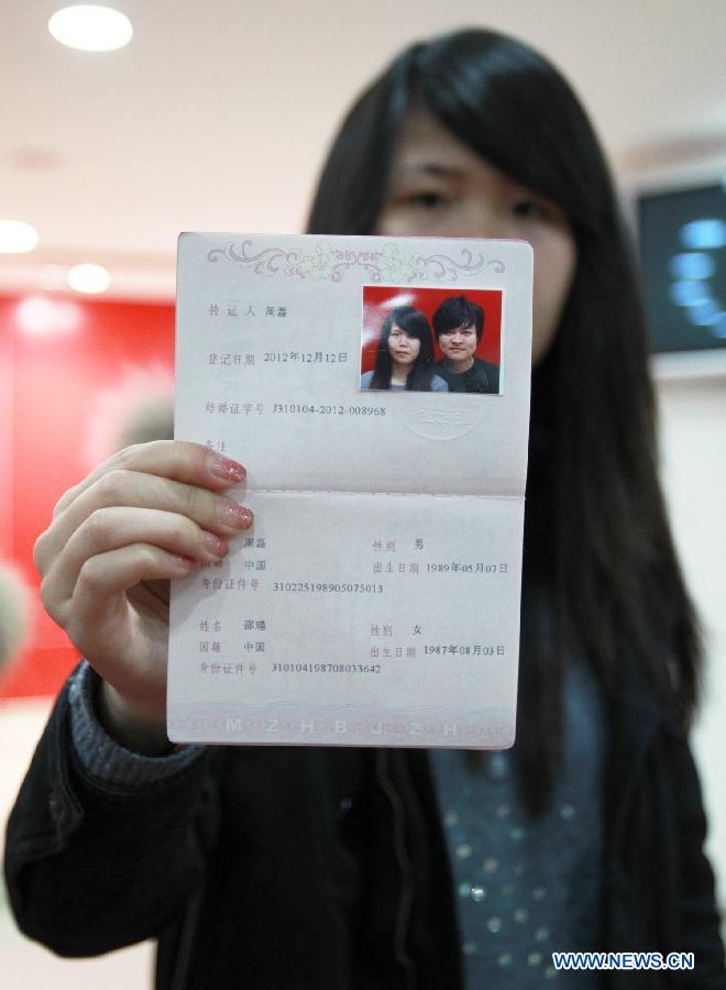 A woman shows her marriage certificate in Shanghai, east China, Dec. 12, 2012. Chinese couples rushed to tie the knot on Wednesday, believing the day to be an auspicious one, as the date sounds like a promise of love when said in Chinese. (Xinhua/Ding Ding)