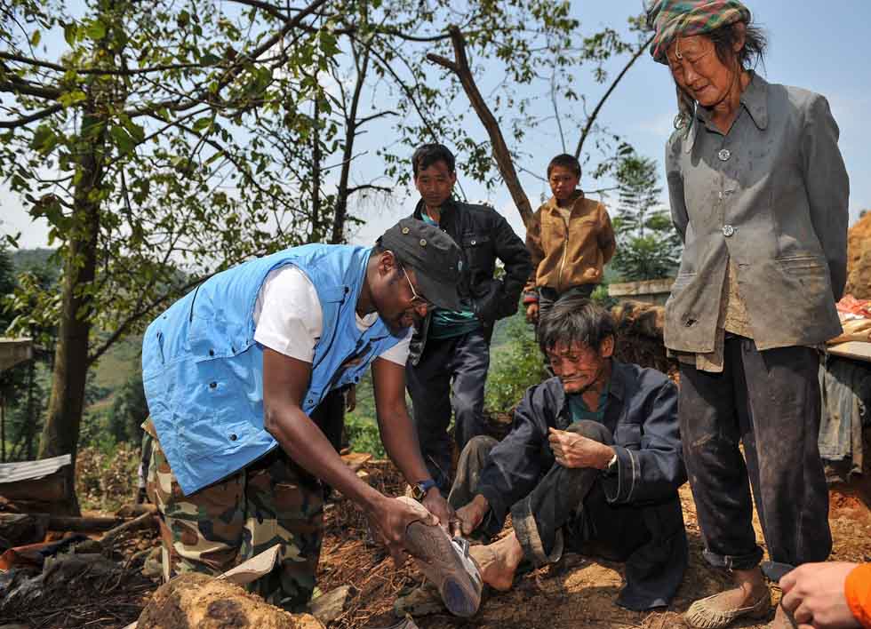 Diarra Boubacar (L) gives his own shows to an old villager whose shoes are broken in Boyi Village, Luozehe Town, Yiliang County, southwest China's Yunnan Province, Sept. 15, 2012.(Xinhua/Li Xin)