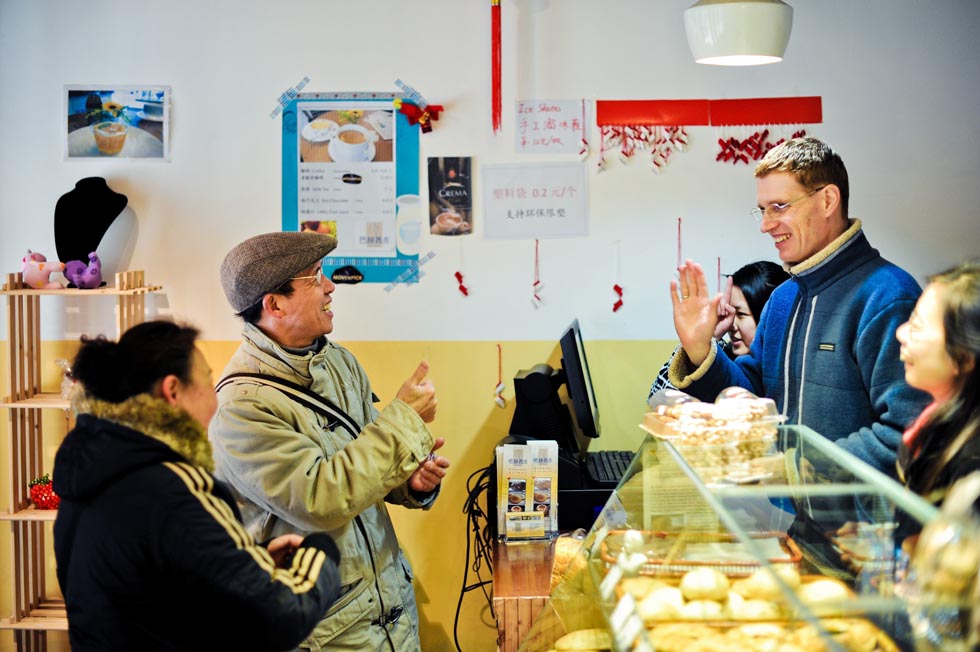 Uwe Brutzer (2nd R) communicates with a deaf-mute customer at his "Bach's Bakery" in Changsha, capital of central China's Hunan Province, Feb. 8, 2012.(Xinhua/Bai Yu)