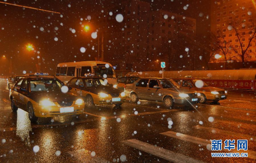 Cars wait for green light in snow at a crossroad in Beijing on Dec. 13, 2012. A heavy snow battered the city on Thursday night. (Photo/Xinhua)