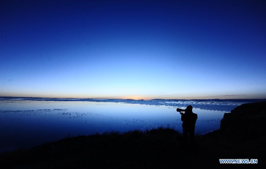 An amateur photographer takes photos of the sunrise scenery on the Bird Island of Qinghai Lake in northwest China's Qinghai Province on Dec. 12, 2012. The Qinghai Lake, China's largest inland salt water lake, presents a beautiful scenery in winter. (Xinhua/Zhang Hongxiang)