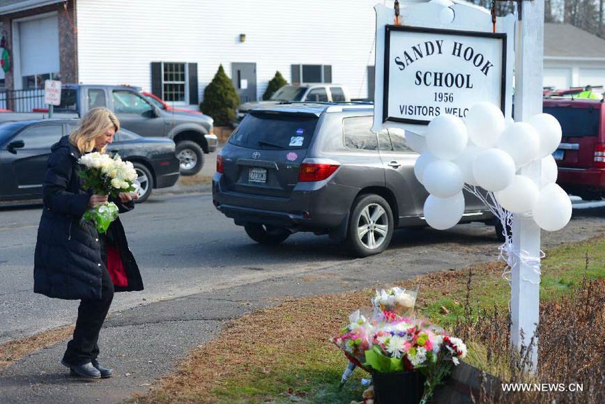 Local resident Jaeger Andrea holds a bunch of flowers near Sandy Hook Elementary School, where a gunman opened fire on school children and staff in Newtown, Connecticut, Dec. 15, 2012. A shooting incident on Friday morning in the elementary school in Newtown of the Connecticut State of the United States killed at least 28 people, including 20 children. (Xinhua/Wang Lei) 