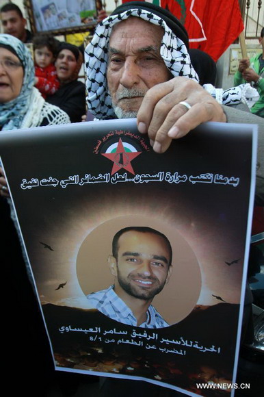 Palestinians attend a rally calling for the release of two Palestinian prisoners in Israeli jails, in the West Bank city of Nablus on Dec. 17, 2012. The two prisoners, Ayman Sharawneh and Samer Isawi, have been going on a hunger strike for over four months in Israeli jails against their administrative detention. (Xinhua/Nidal Eshtayeh)  