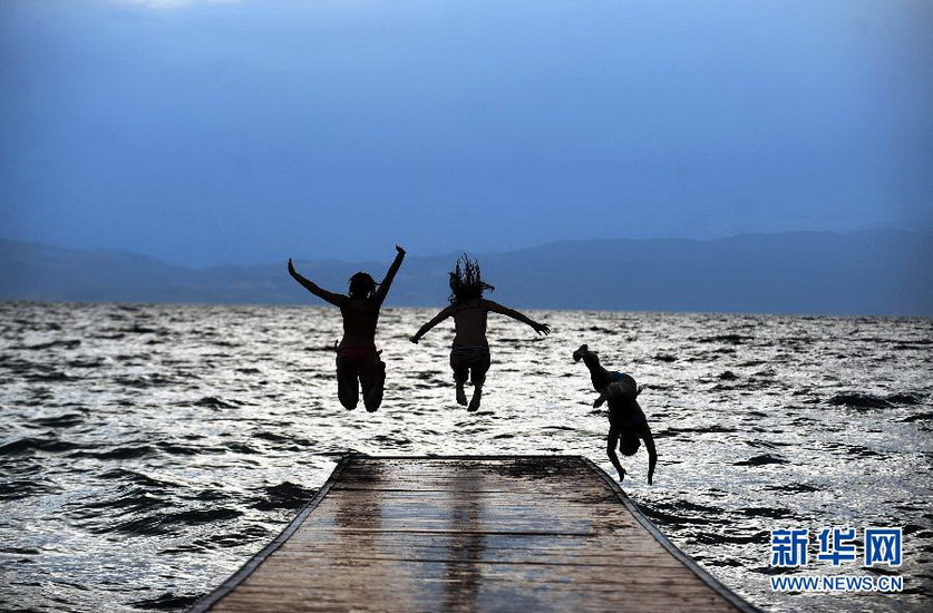 Three girls jump into Lake Ohrid at sunset in Macedonia on July 12, 2012 (Xinhua/AFP)