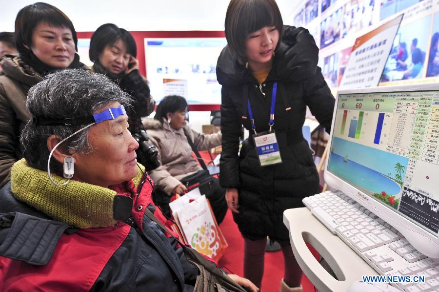 An old woman tries a test device during the Beijing International Senior Industry Expo 2012 in Beijing, capital of China, Dec. 19, 2012. The three-day expo opened here on Wednesday, showcasing products and services for senior citizens. (Xinhua/Wang Jingsheng)